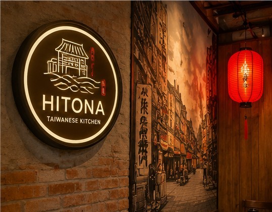 Biển hiệu tròn Hitona trên tường gạch cạnh tranh phố cổ và đèn lồng